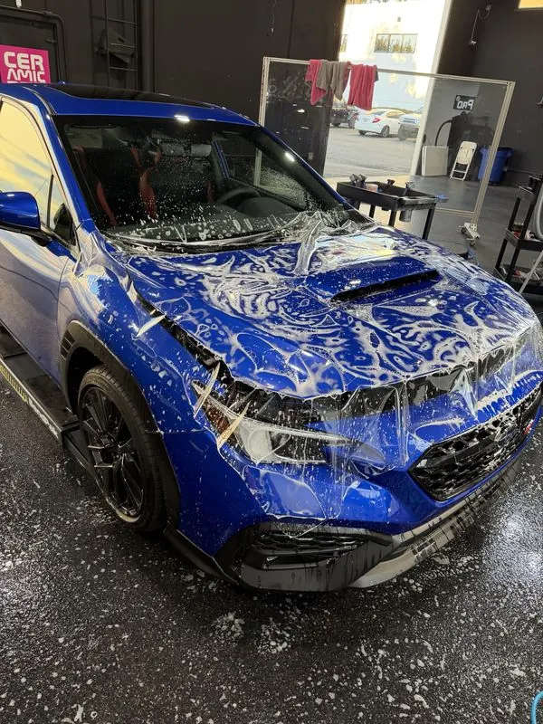Paint protection film being installed on a blue Subaru WRX