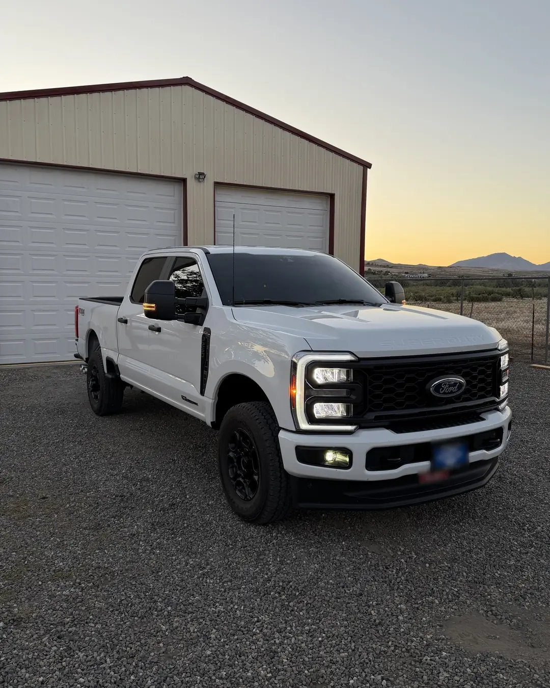 White Ford Super Duty with tinted windows at sunset