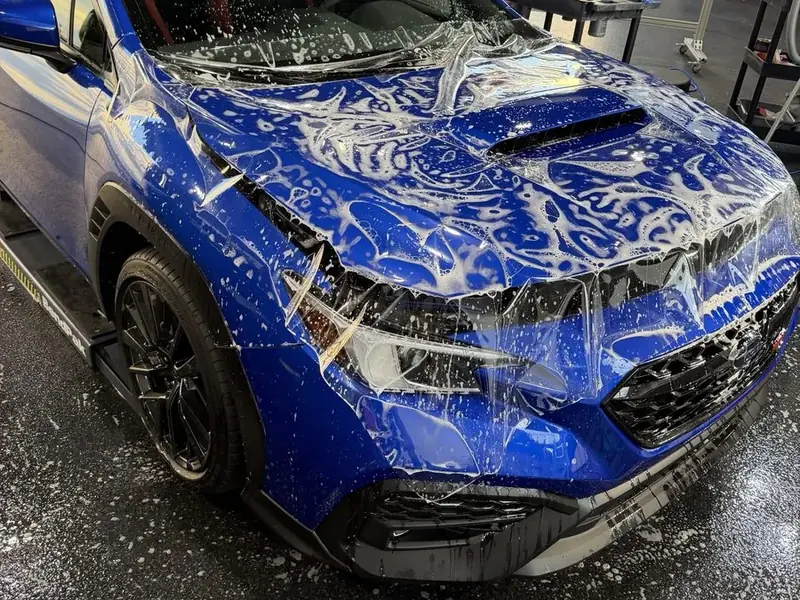 Paint protection film being installed on a blue Subaru WRX